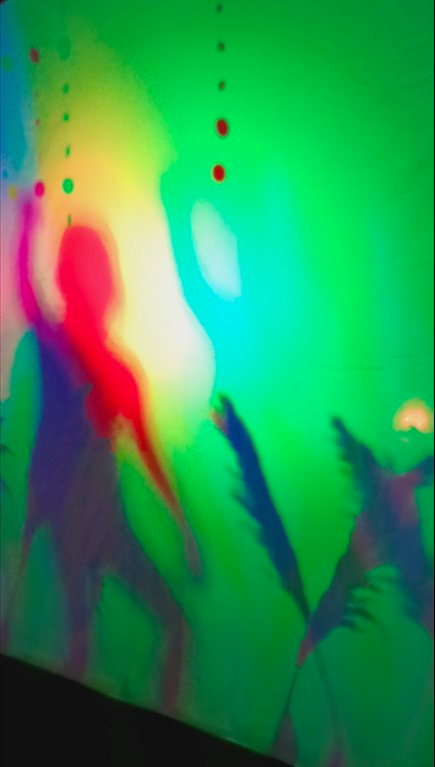 A little girl dancing in a colorful shadow installation.